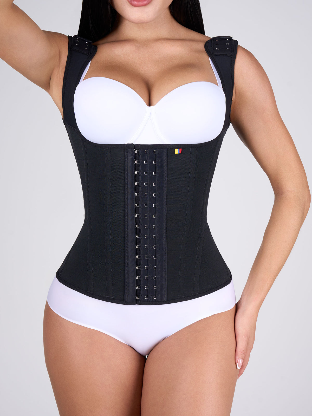 Woman wearing the black Shaping Vest, Colombian shapewear with front hooks and adjustable straps that shape the torso, slim the waist and support the back. #color_Black