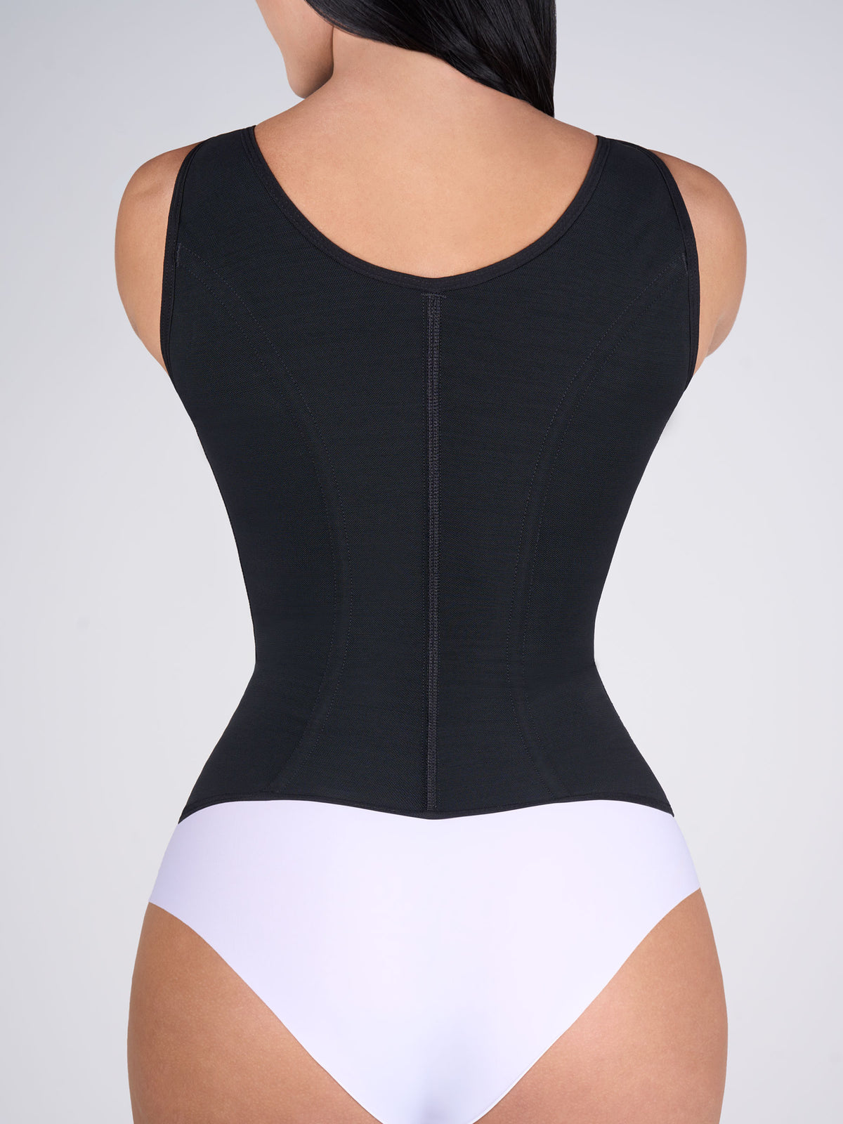 Woman showing the back of the black Shaping Vest, Colombian shapewear that supports the back and shapes the figure naturally #color_Black