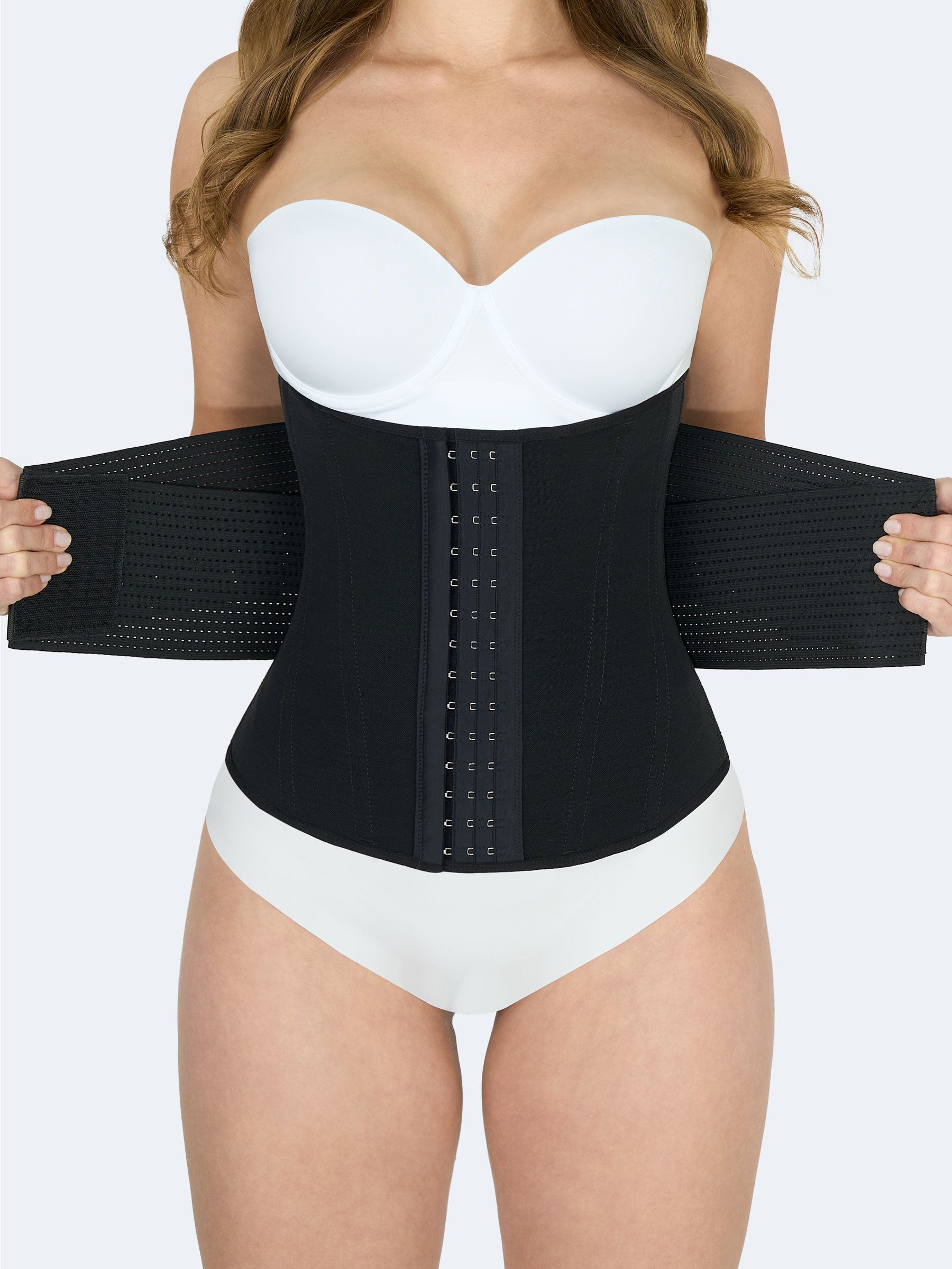 Mujer usando Cinturilla Reloj de Arena con Elásticos en color negro, Faja Colombiana con broches frontales y elásticos laterales abiertos que permiten ajuste personalizado y mayor compresión #color_Black / Negro