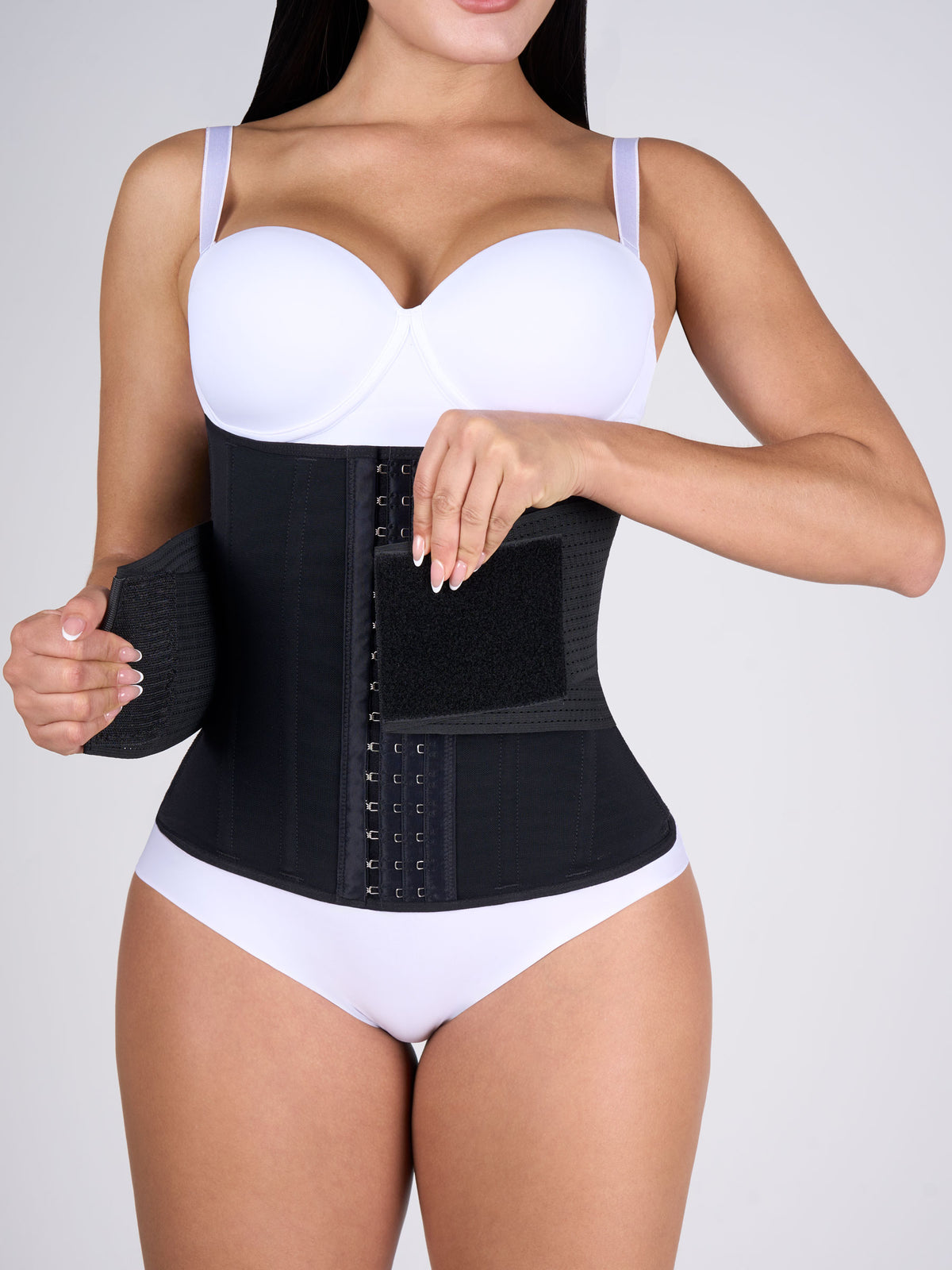 Woman wearing the black Hourglass Waist Cincher with Elastics, Colombian shapewear with front hooks and open side elastics for a custom fit and extra compression #color_Black