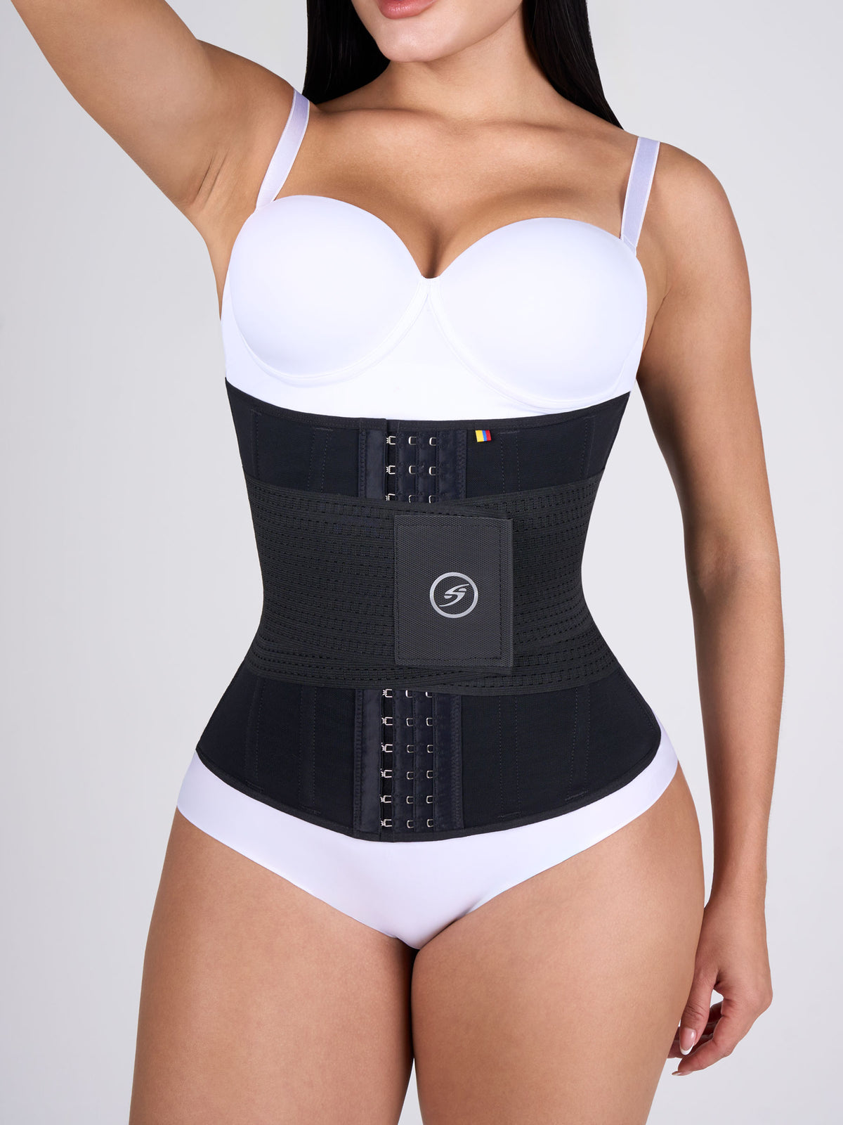 Woman wearing the black Hourglass Waist Cincher with Elastics, Colombian shapewear with front hooks and a velcro band that shapes the waist and adds compression #color_Black
