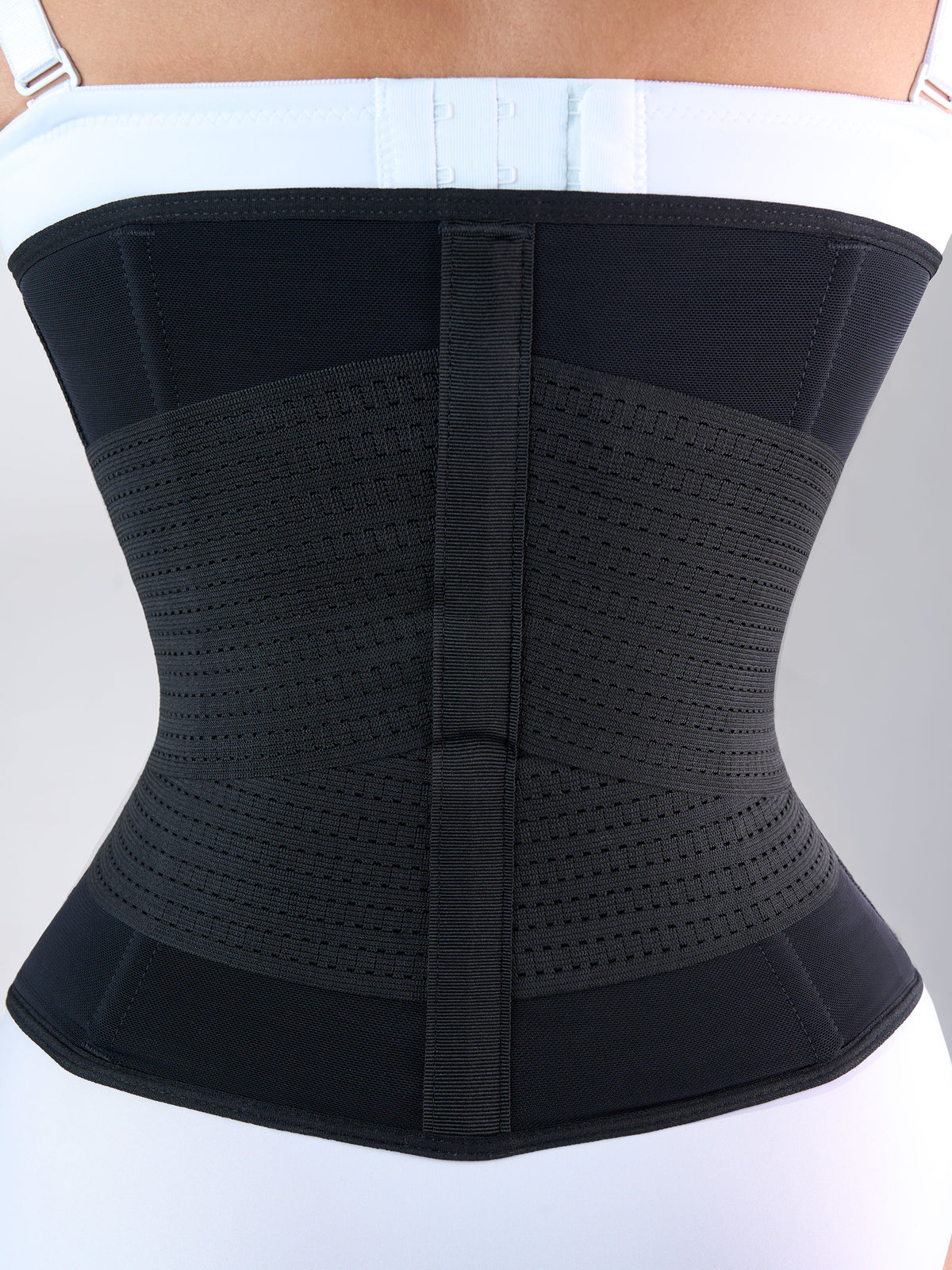 Woman showing the back of the black Hourglass Waist Cincher with Elastics, Colombian shapewear that defines the waist and supports the lower back #color_Black