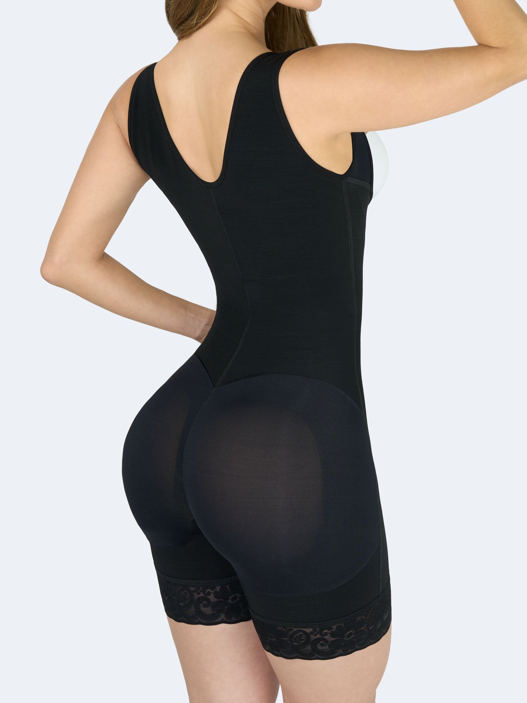 Mujer usando faja colombiana full body con cierre color negro, vista tres cuartos posterior, efecto levanta cola y control de cintura. #color_Black / Negro