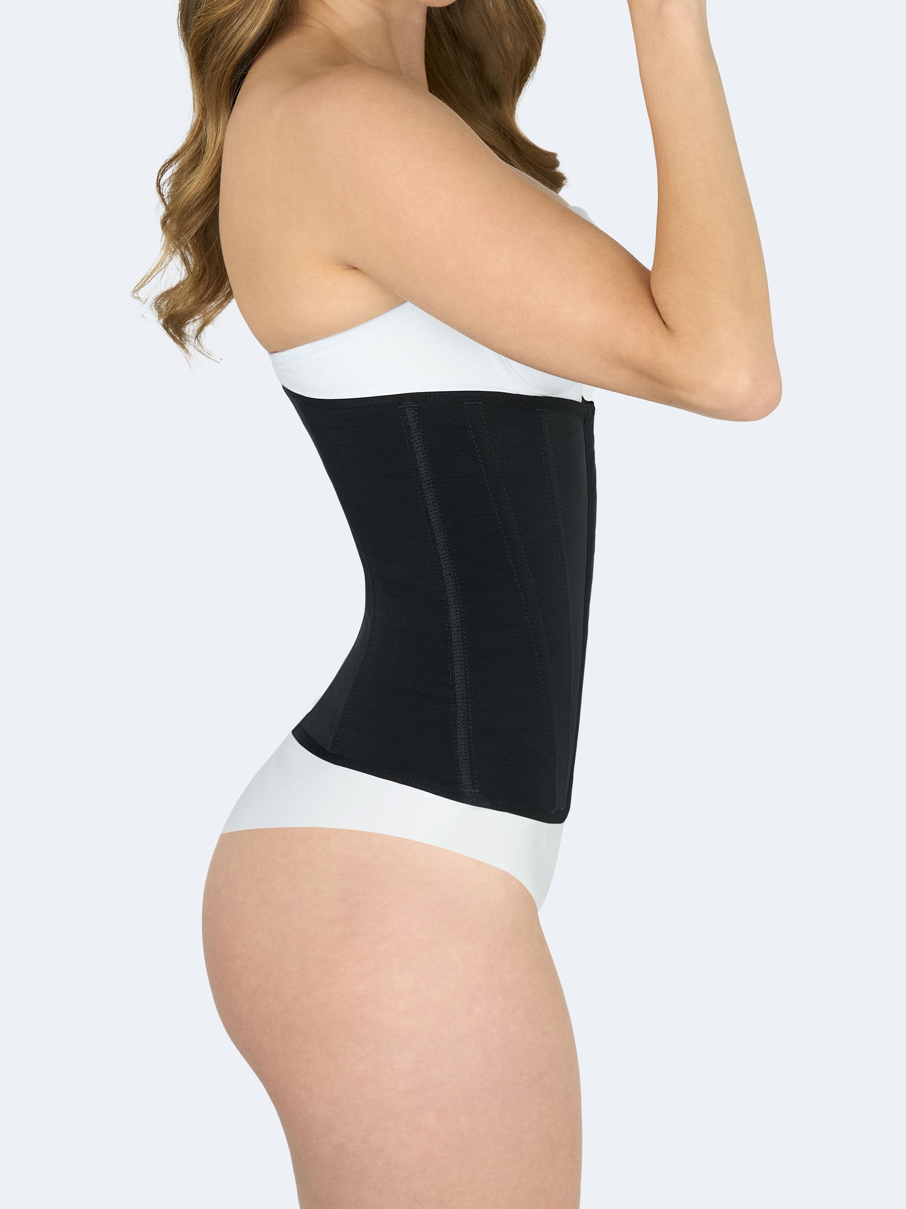 Mujer mostrando cinturilla moldeadora en color negro, Faja Colombiana vista lateral que estiliza cintura y ofrece compresión abdominal. #color_Black / Negro