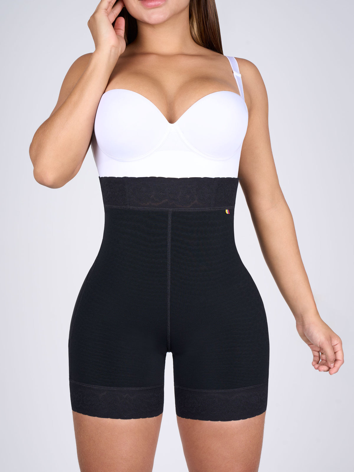 Woman wearing black high-waisted butt-lifting shorts, Colombian shapewear with floral lace at the waist and thighs that shapes the tummy and enhances the figure #color_Black