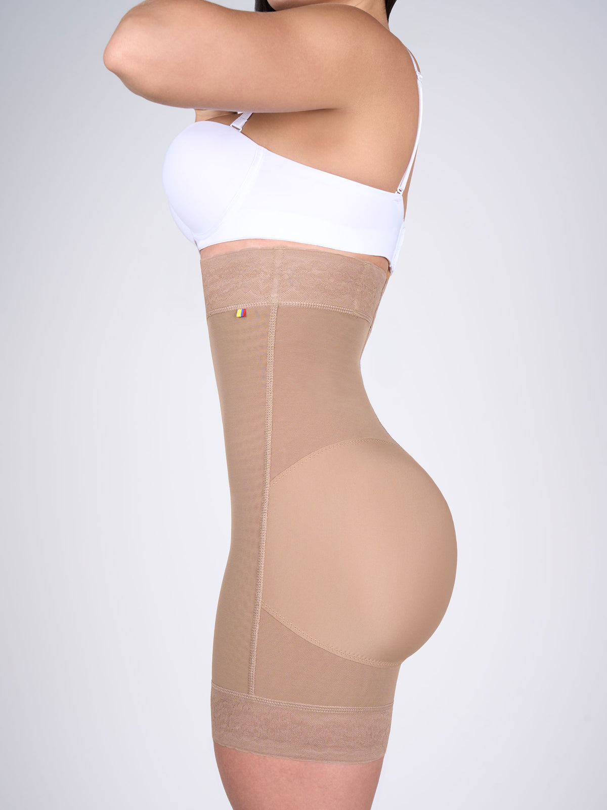Woman wearing mocha high-waisted butt-lifting shorts, Colombian shapewear that defines the waist, shapes the hips and lifts the glutes, with floral lace on the thighs #color_Mocha