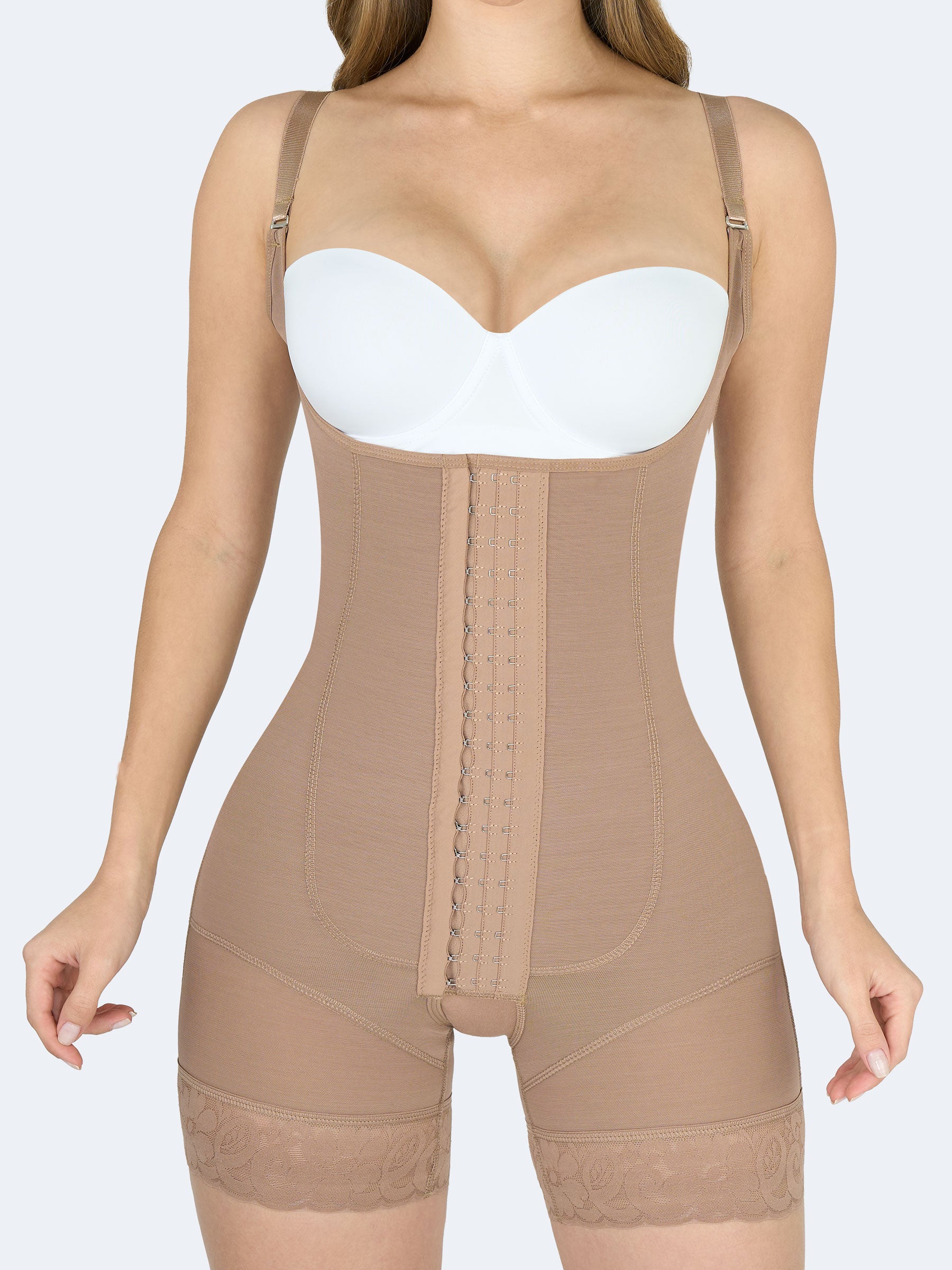 Mujer de frente usando faja colombiana full body con tirantes en color moca, cierre frontal con broches, realce de glĂșteos y encaje en los muslos #color_Mocha / Moca