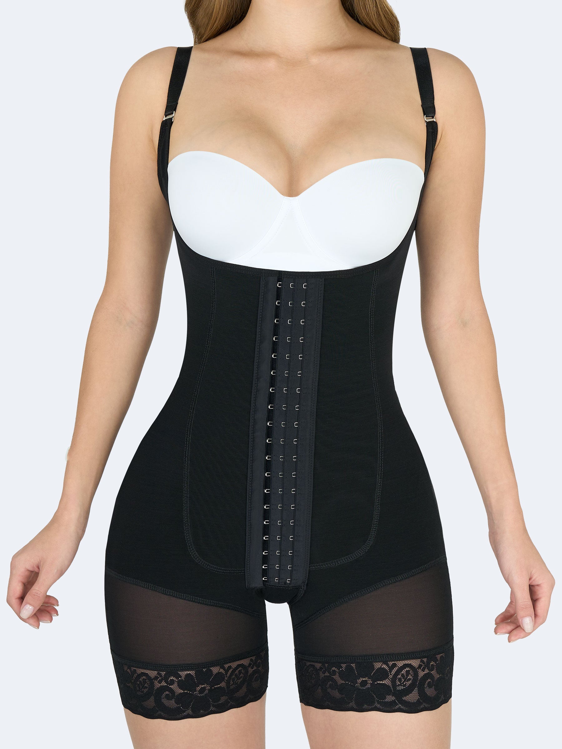 Mujer de frente usando faja colombiana full body con tirantes en color negro, broches frontales de compresiĂłn, realce de glĂșteos y encaje en los muslos. #color_Black / Negro
