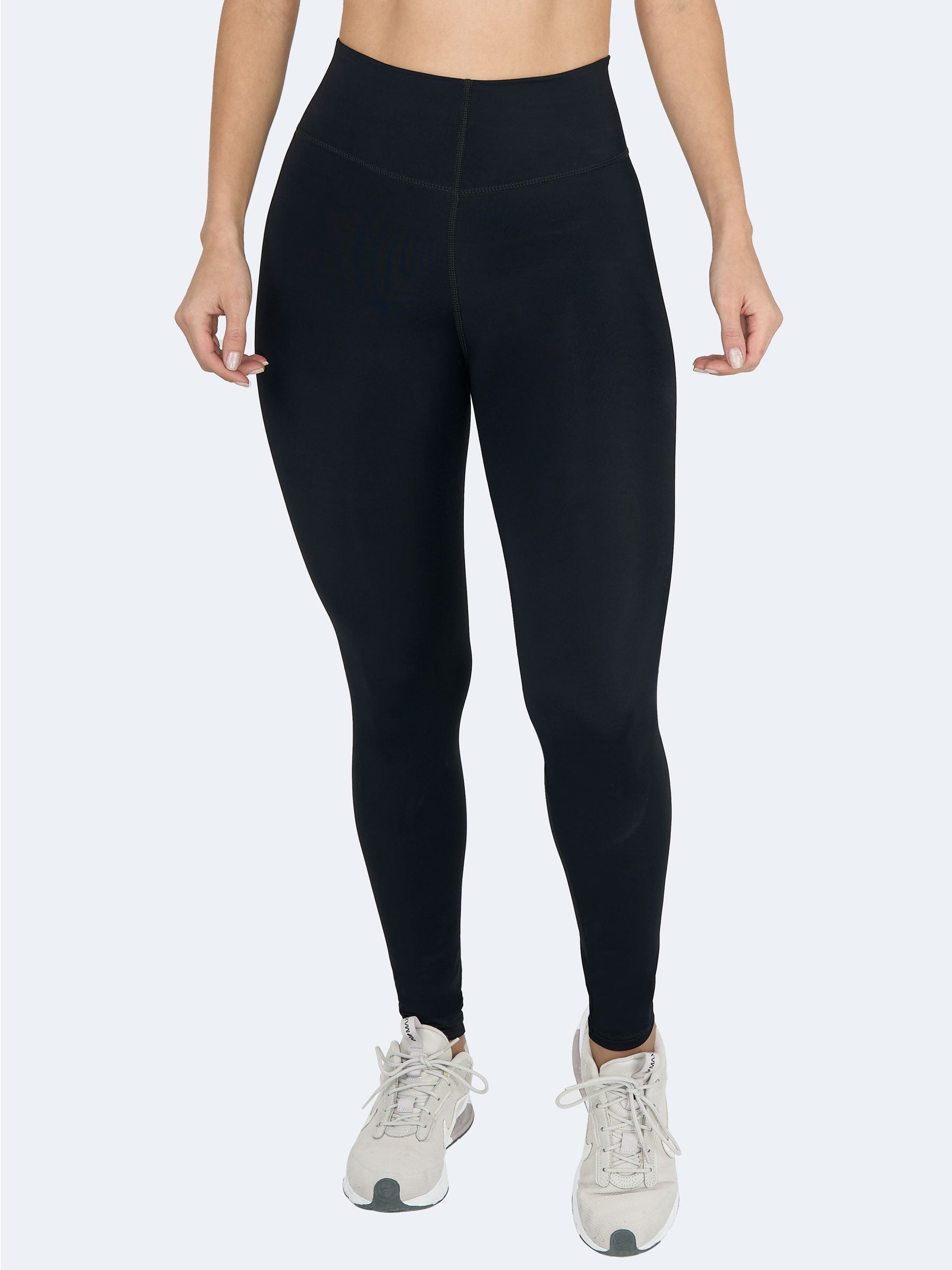 Vista frontal de mujer usando leggings negros levanta cola de talle alto, hechos en Colombia, que definen la cintura y estilizan piernas #color_Black / Negro
