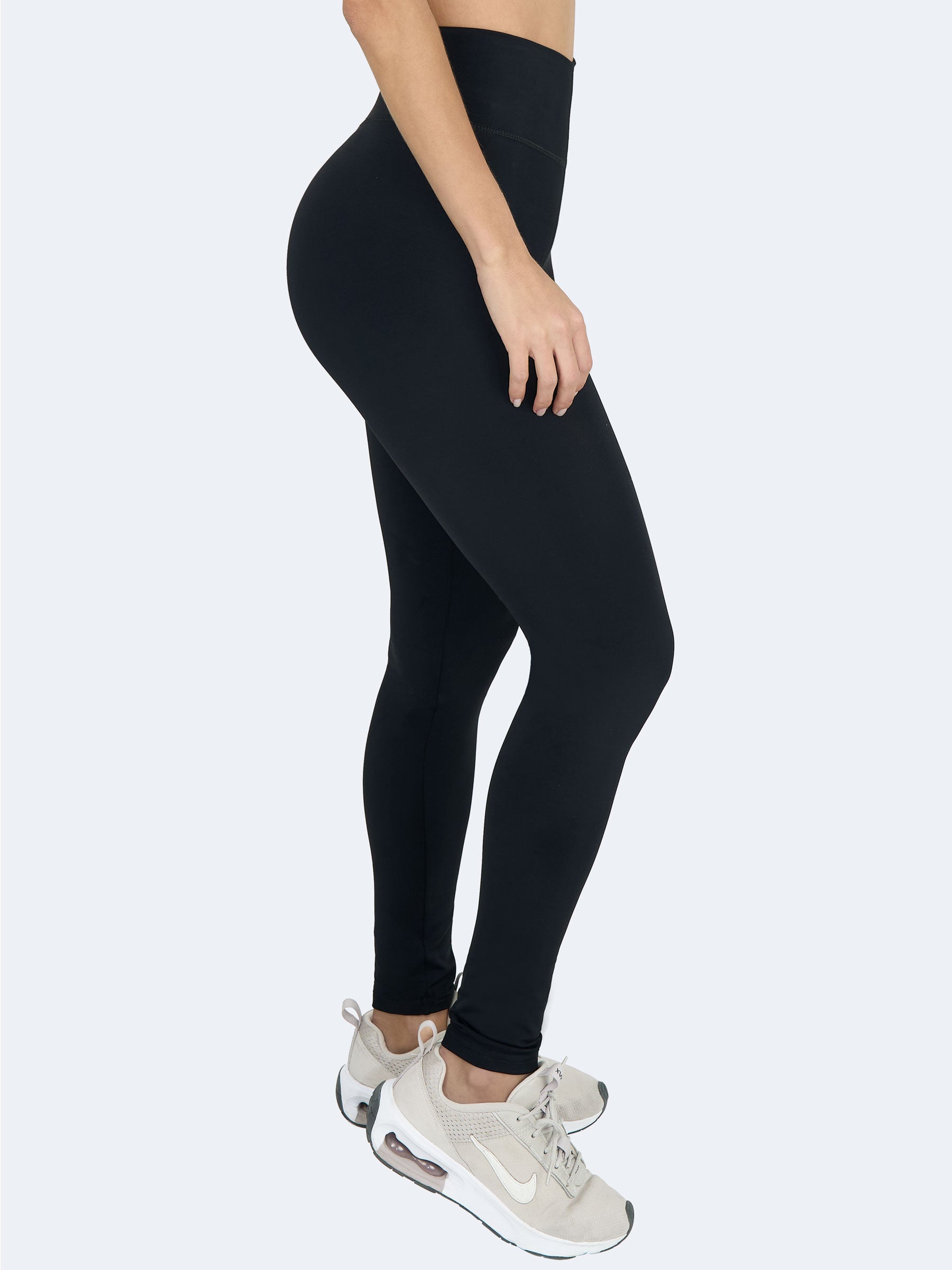 Vista lateral de mujer usando leggings negros levanta cola de talle alto, hechos en Colombia, que realzan glĂșteos y estilizan la figura #color_Black / Negro