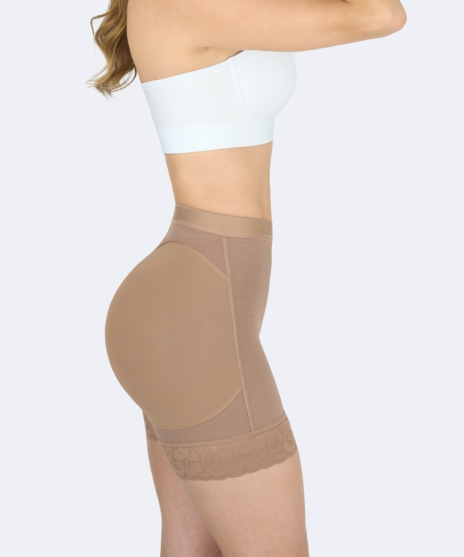 Mujer de perfil usando short color moca de fajas colombianas levanta cola para moldear cintura y glúteos