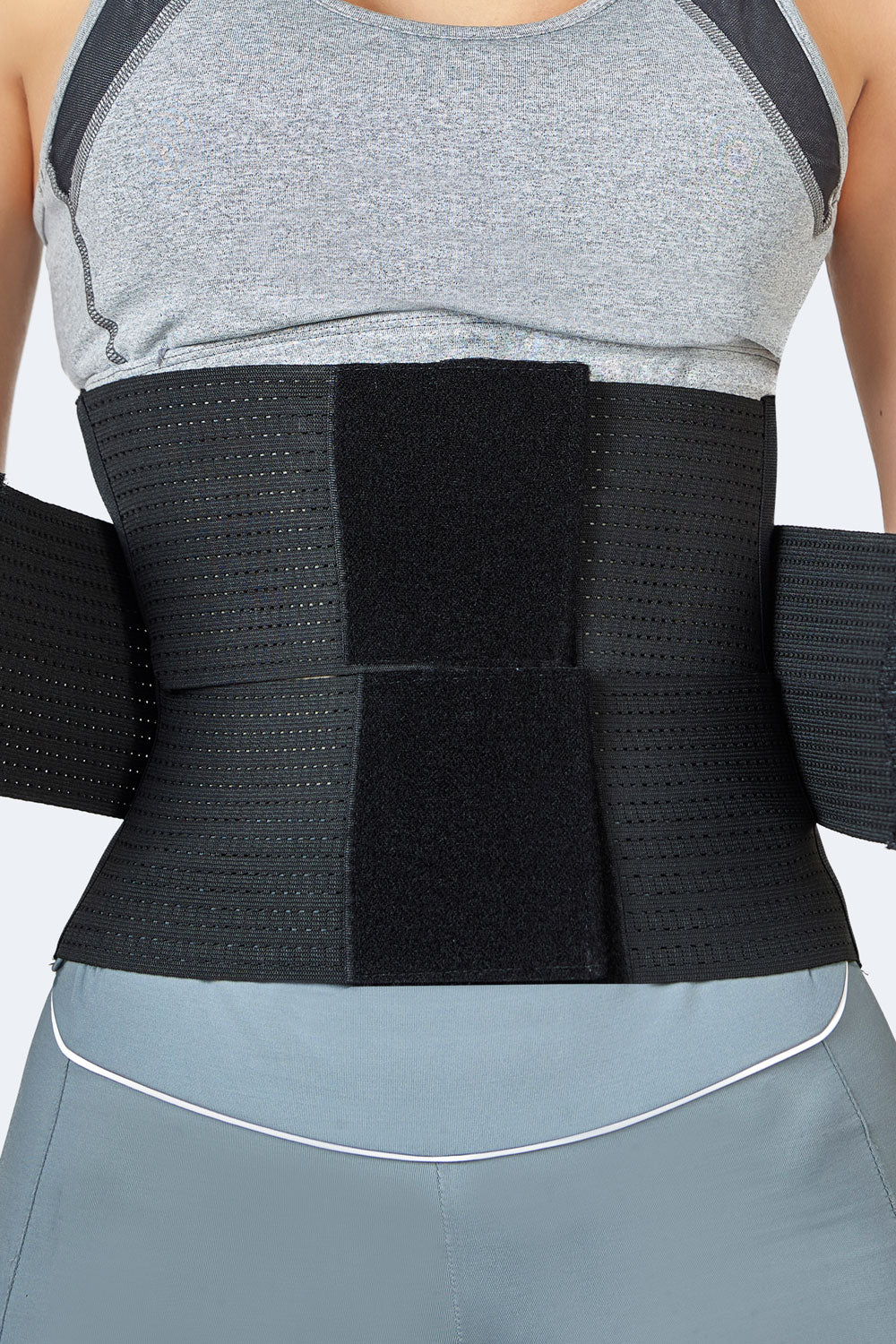 Mujer usando cinturon elastico negro, faja colombiana deportiva para compresion abdominal con ajuste de velcro frontal.