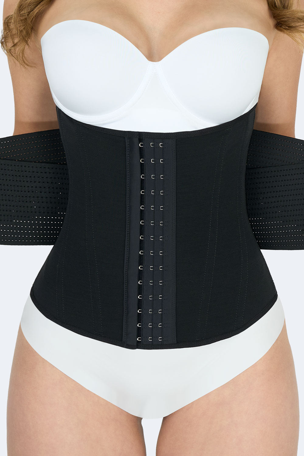 Vista frontal cercana de la Cinturilla Reloj de Arena con Elásticos en color negro, Faja Colombiana con tres niveles de broches y bandas elásticas laterales que permiten compresión ajustable