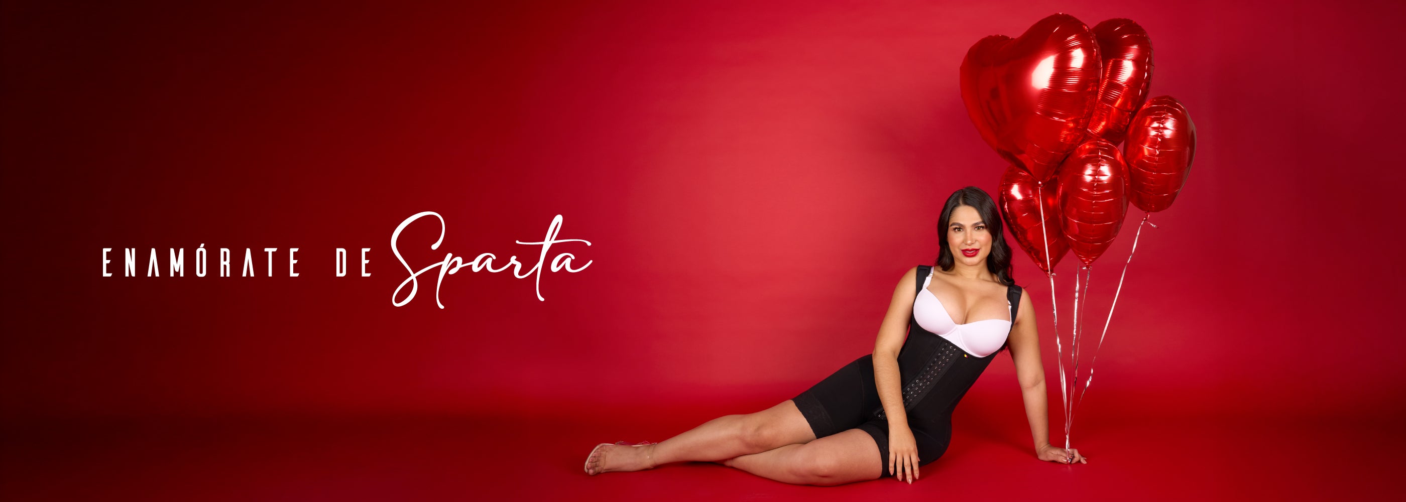 Mujer usando faja colombiana de alta compresión, full body con varillas y broches color negro para moldear la cintura y abdomen. Sostiene un globo rojo en forma de corazón. 