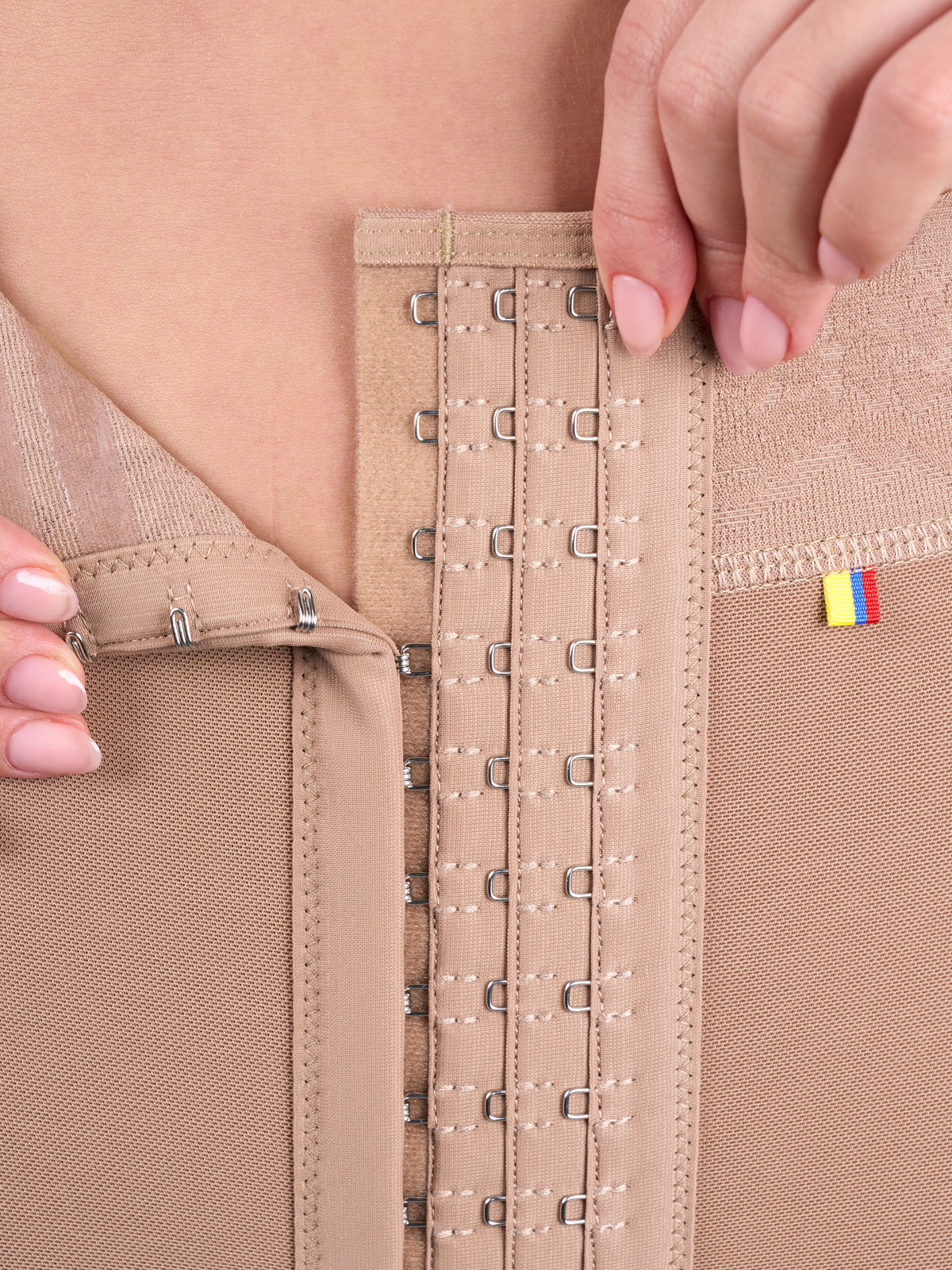 Detail of the front hook closure with 3 levels of adjustment on the mocha high-waisted butt-lifting shorts, Colombian shapewear that lets you adjust the compression to define the waist