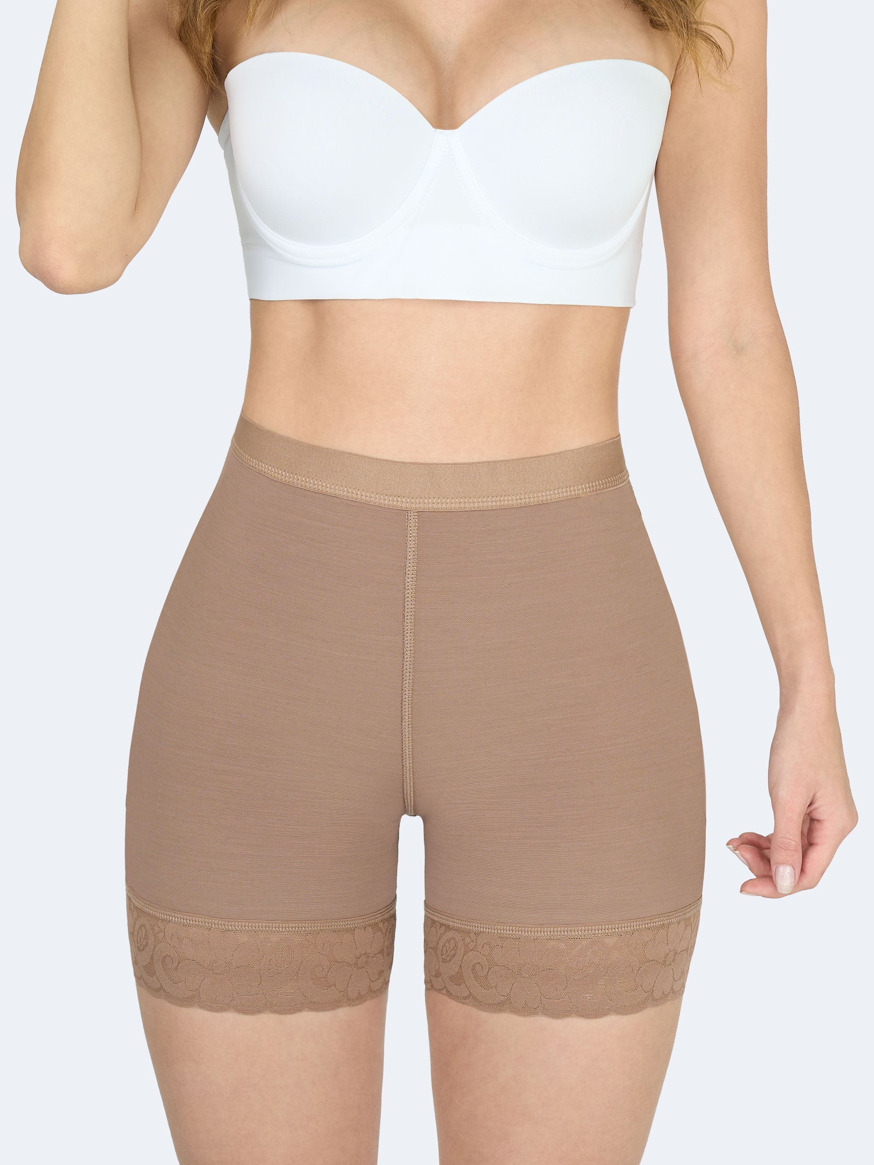 Mujer mostrando short levanta cola corto en color cocoa, Faja Colombiana de tiro medio que define el abdomen, moldea caderas y realza glúteos con encaje floral en los muslos #color_Mocha / Moca
